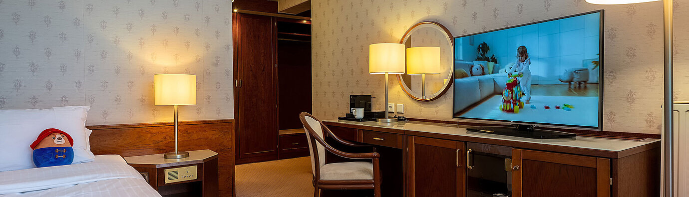 Superior Familienzimmer Superior Familienzimmer mit Bett, großem TV, Schreibtisch und gemütlicher Sitzecke für einen entspannten Aufenthalt.