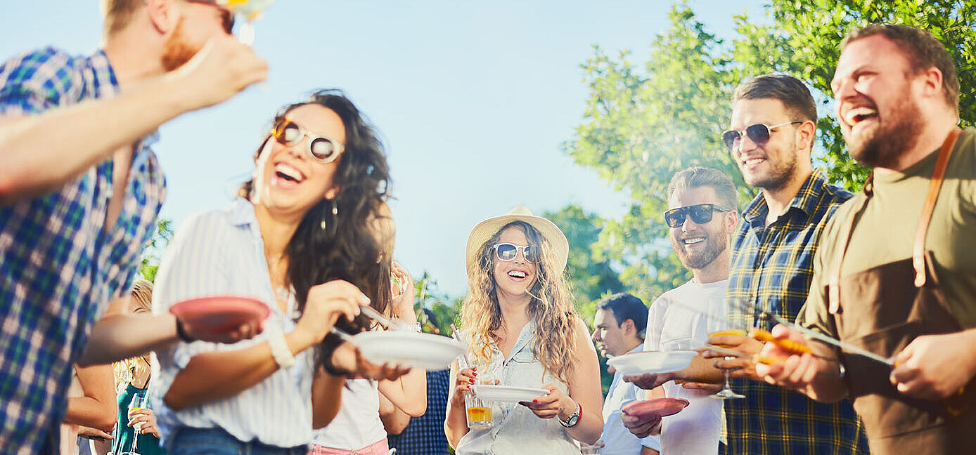 © chika milan - AdobeStock.com Freunde lachen und feiern gemeinsam bei einer sommerlichen Grillparty im Freien