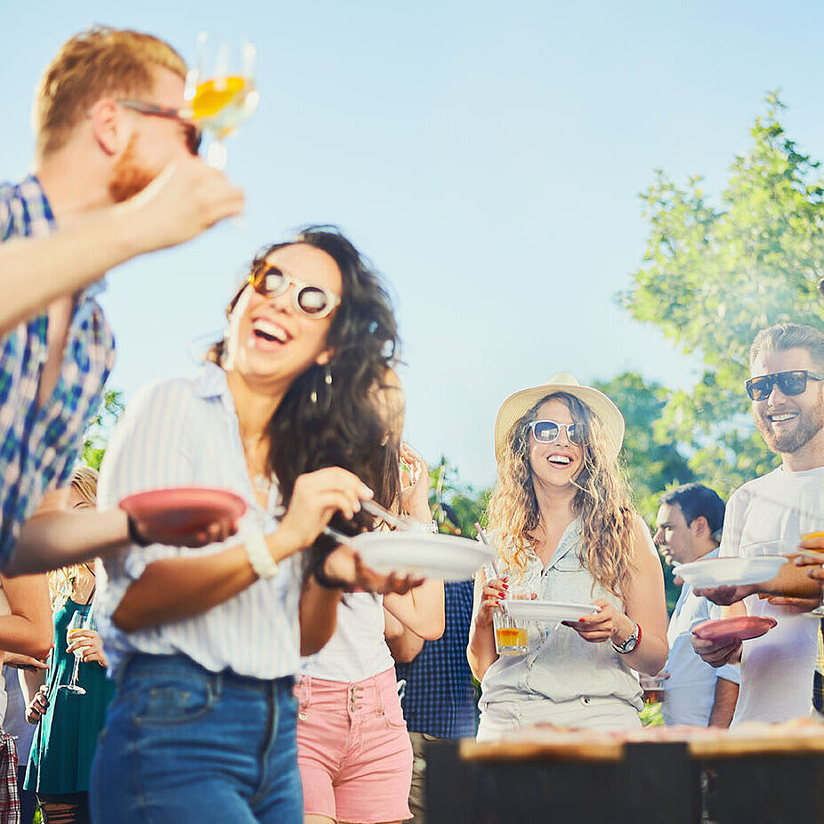 © chika milan - AdobeStock.com Freunde lachen und feiern gemeinsam bei einer sommerlichen Grillparty im Freien