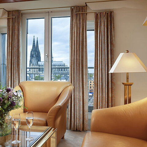 Elegante Heumarkt-Suite im Maritim Hotel Köln mit komfortablen Ledersesseln und direktem Blick auf den Kölner Dom.