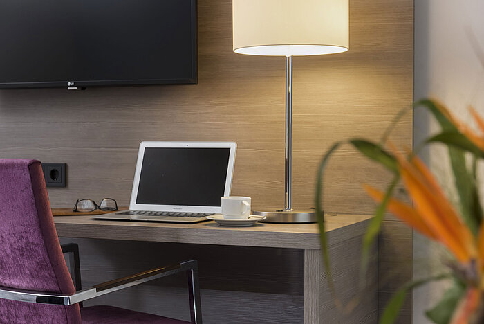 Schreibtisch im Maritim Hotel Königswinter mit Laptop, Lesebrille und eleganter Tischlampe.