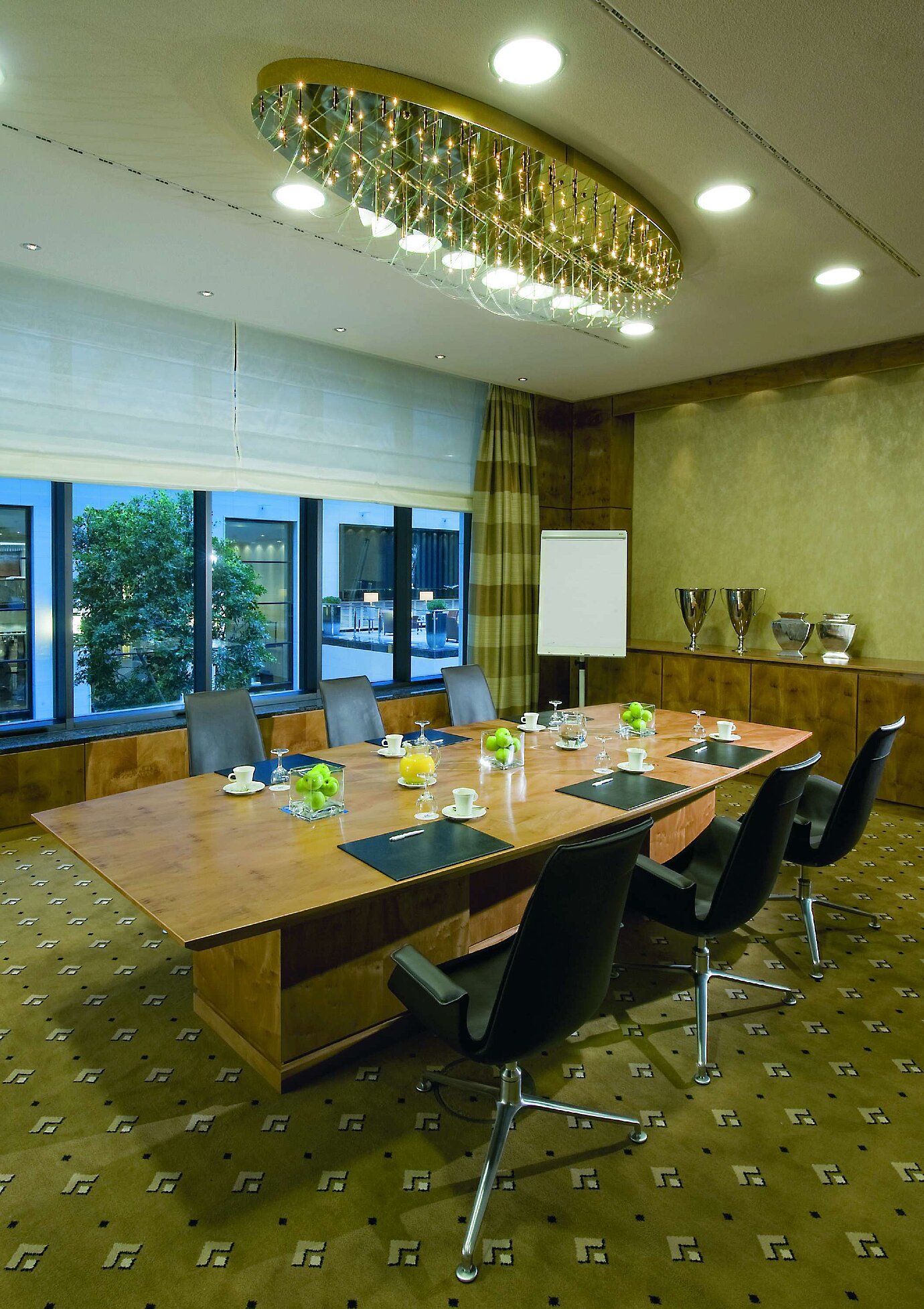 Moderner Meetingraum im Maritim Hotel Düsseldorf mit edlem Holztisch, komfortablen Stühlen und eleganter Beleuchtung.