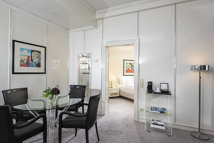Helle Executive Suite im Maritim Hotel Frankfurt mit stilvollem Essbereich, Glas-Tisch und direktem Zugang zum Schlafzimmer.