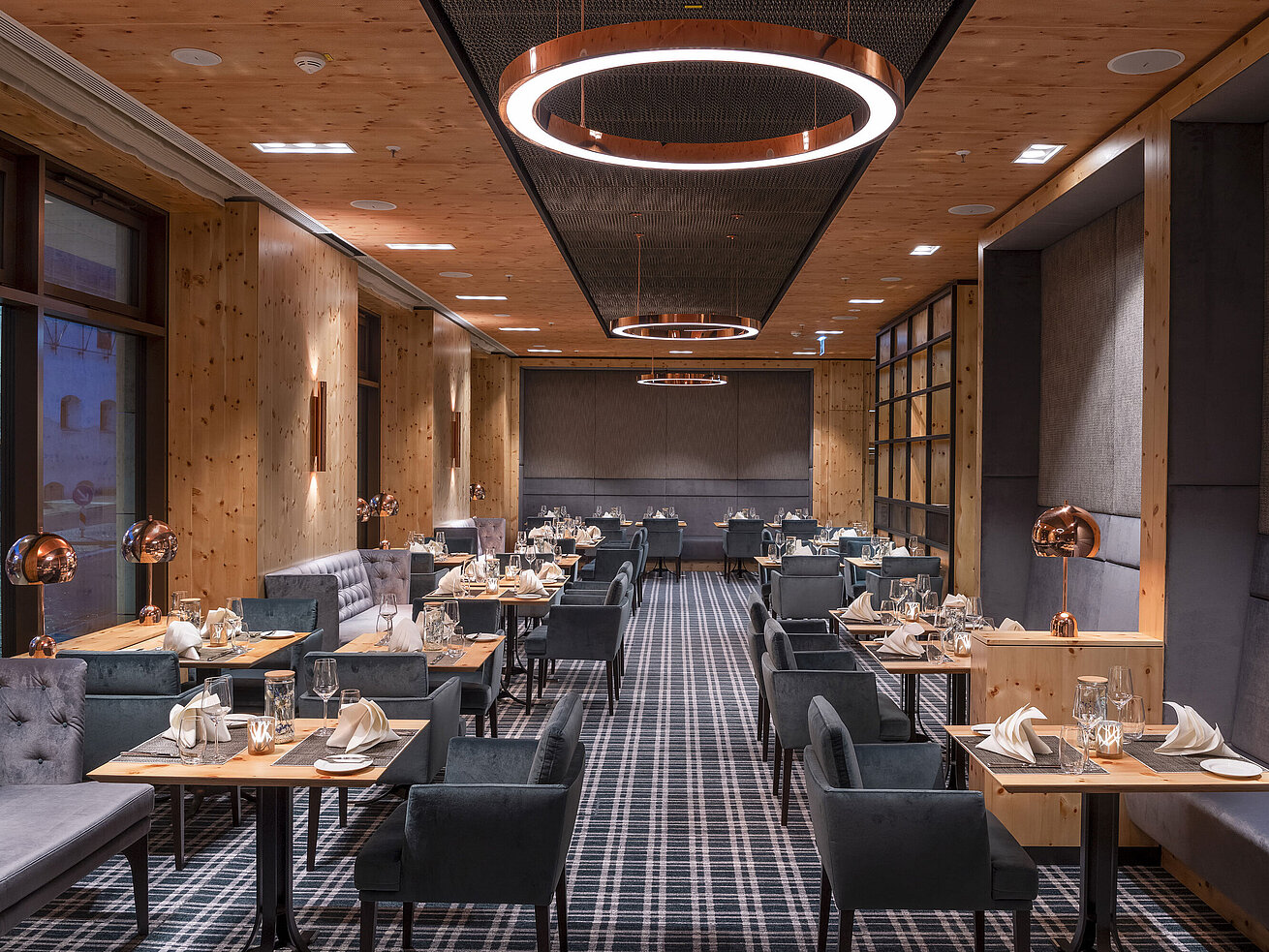 Elegantes Restaurant mit Holzdesign, gemütlichen Sitzbereichen und stilvoll gedeckten Tischen im Maritim Hotel Ingolstadt.