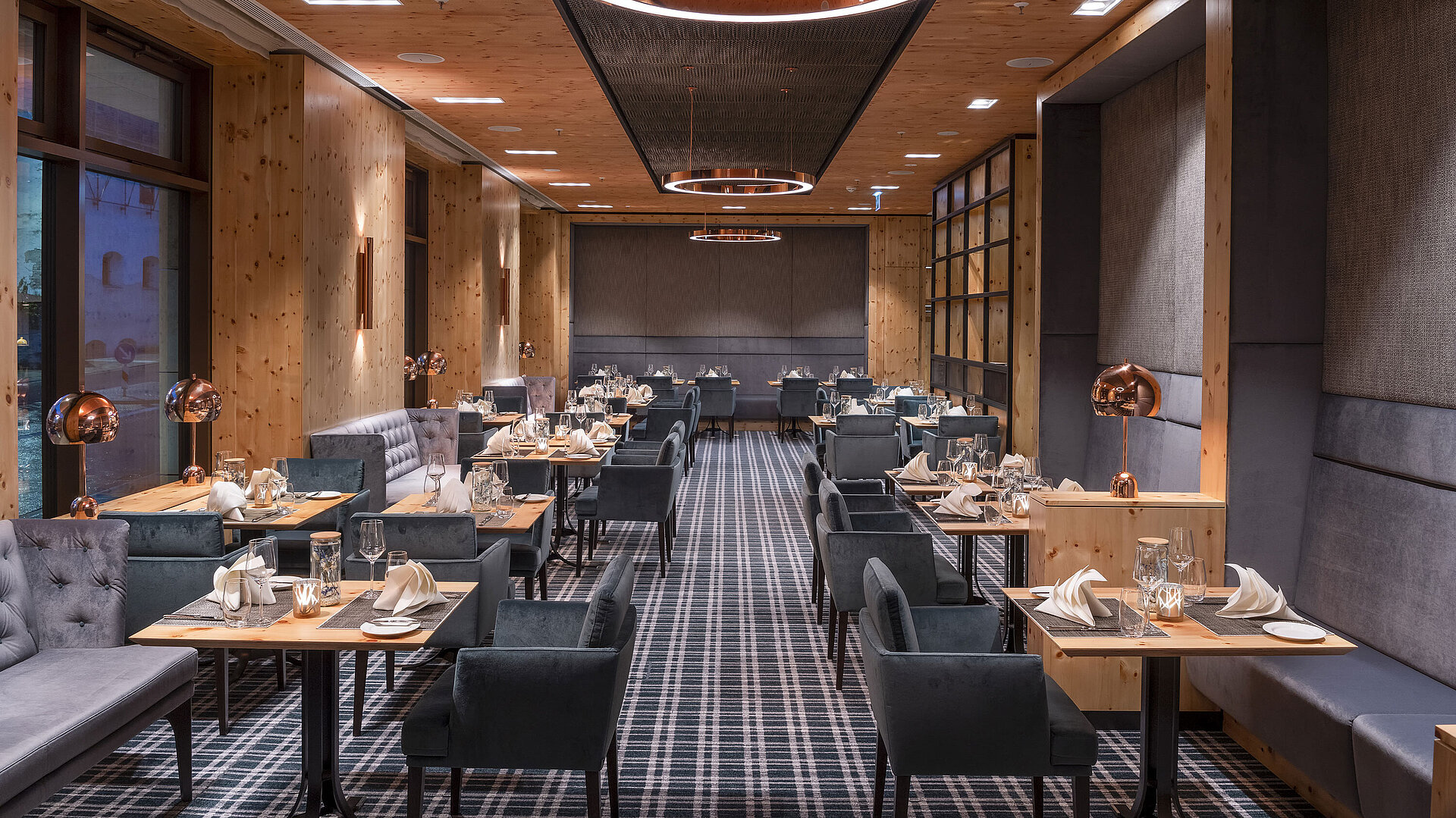 Elegantes Restaurant mit Holzdesign, gemütlichen Sitzbereichen und stilvoll gedeckten Tischen im Maritim Hotel Ingolstadt.