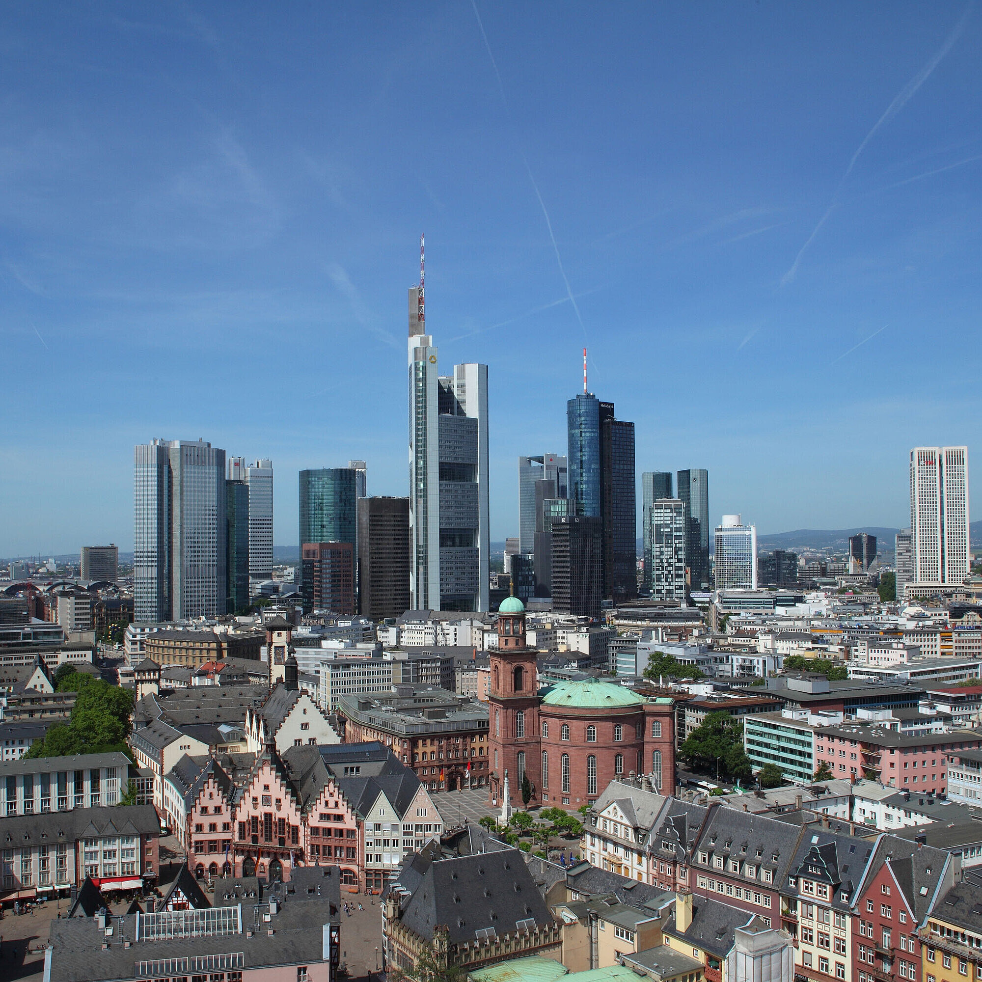 Blick auf die Skyline von Frankfurt mit dem Römer und der Paulskirche im Vordergrund bei klarem Himmel.