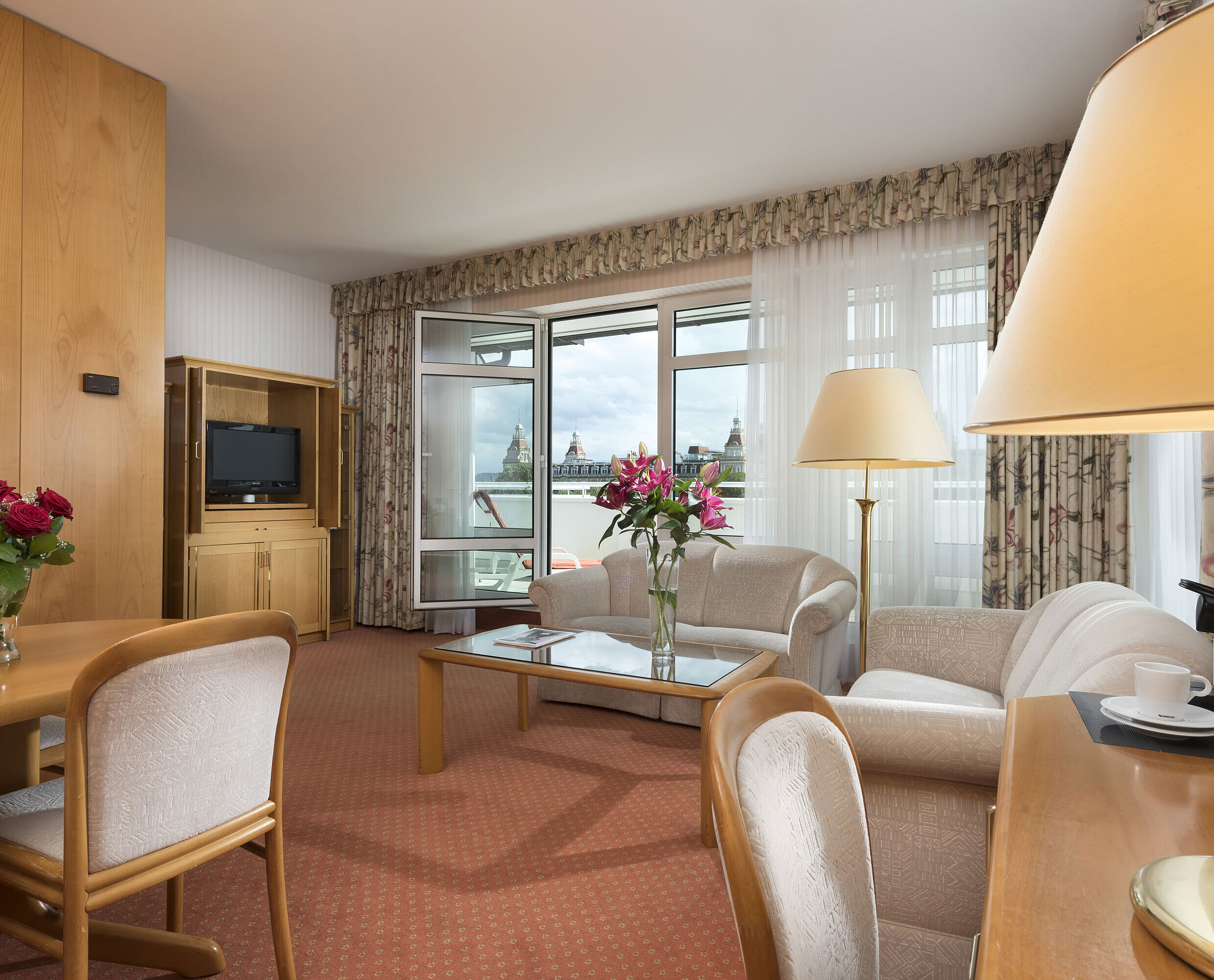 Junior Suite Großzügiger Wohnbereich mit Blumen, Sofa, Esstisch und Ausblick im Maritim Hotel Bad Wildungen