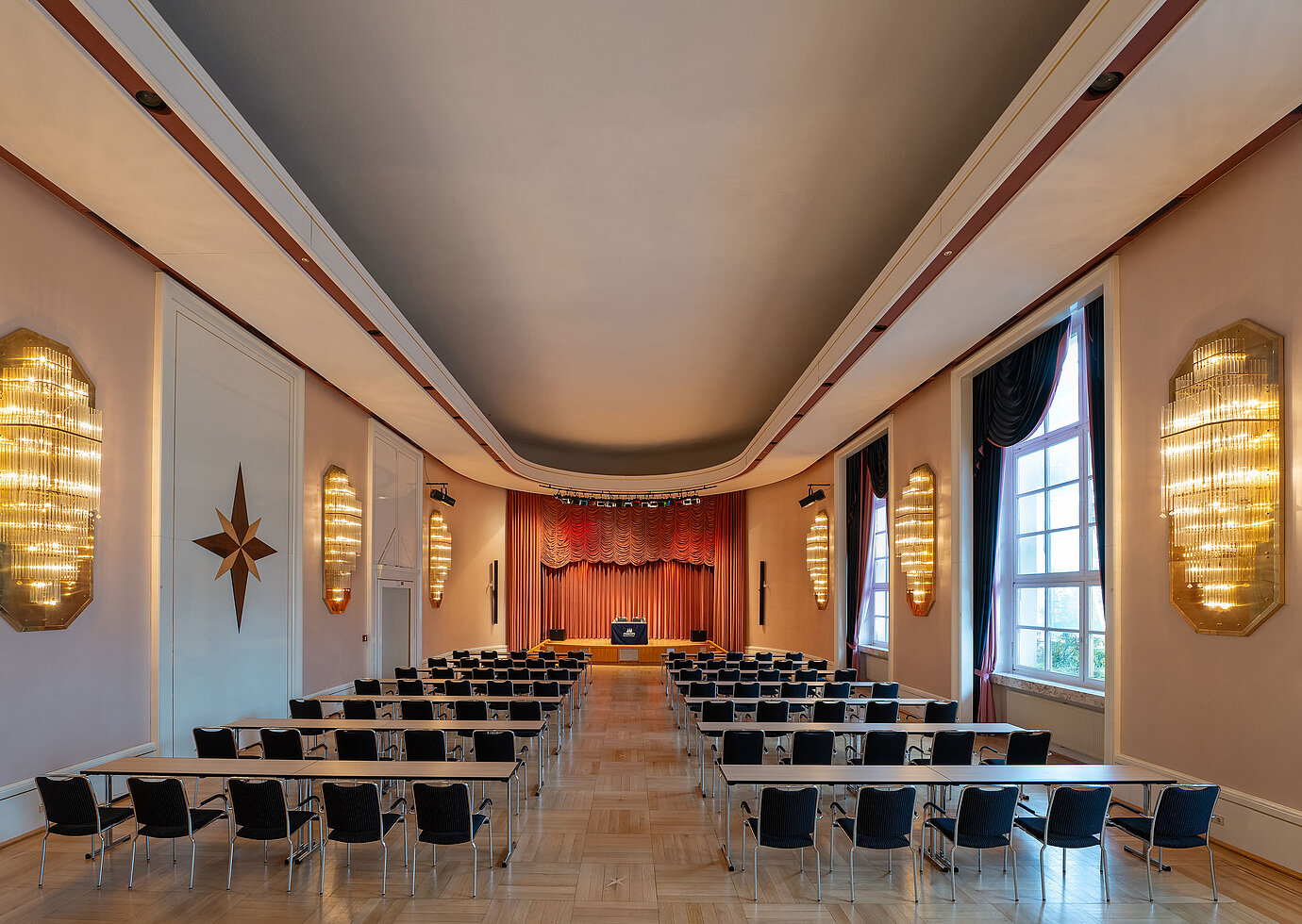 Saal Waldeck im Maritim Hotel Bad Wildungen mit langer Reihenbestuhlung, Bühne und eleganter Beleuchtung.