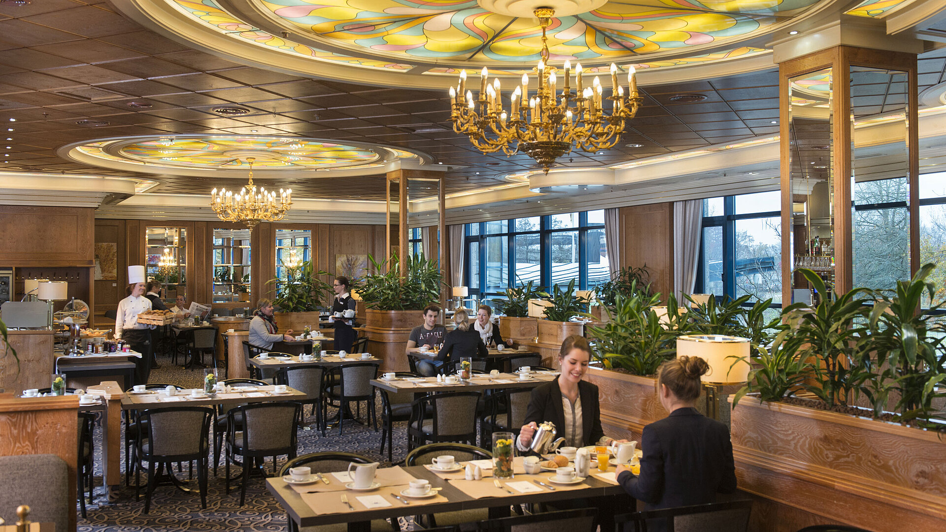 Restaurant "Rôtisserie" mit Front Cooking Gäste genießen Frühstück im stilvollen Restaurant mit Kronleuchtern und großen Fenstern im Maritim Hotel Hannover.