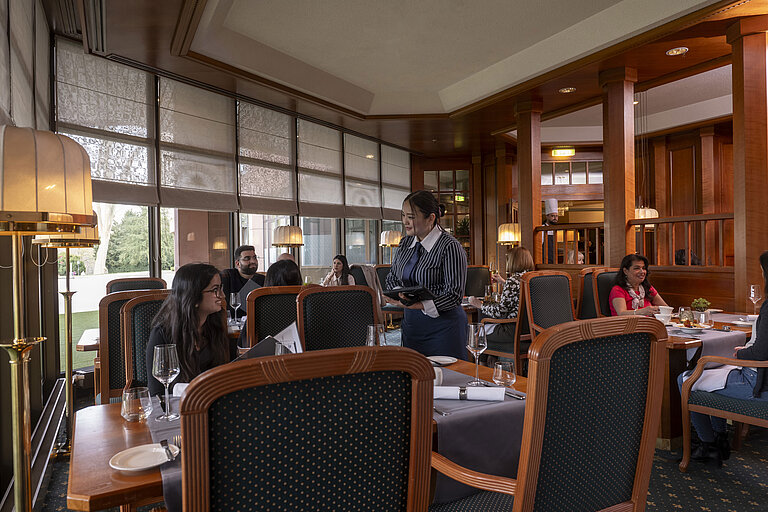 Gäste speisen in dem stilvollen Restaurant des Maritim Hotel Bad Homburg, während freundliches Personal den Service bietet.