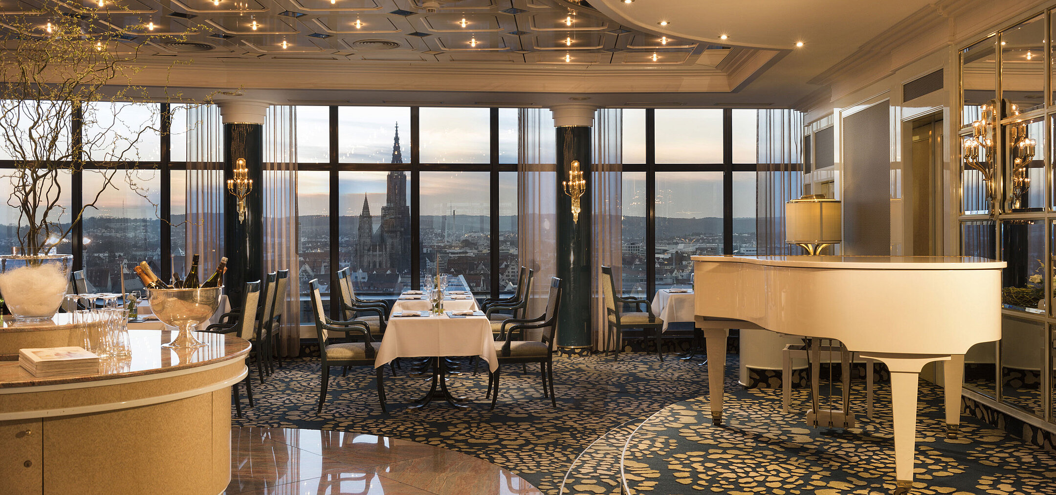 Elegantes Panorama-Restaurant mit Flügel und Blick auf das Ulmer Münster bei Sonnenuntergang