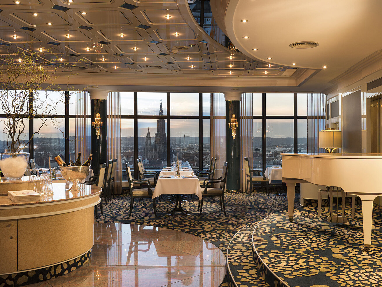 Elegantes Panorama-Restaurant mit Flügel und Blick auf das Ulmer Münster bei Sonnenuntergang