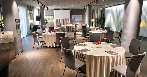 Flexibler Eventraum im Maritim Hotel Plaza Tirana mit runden Tischen, Tageslicht und Blumen auf jedem Tisch