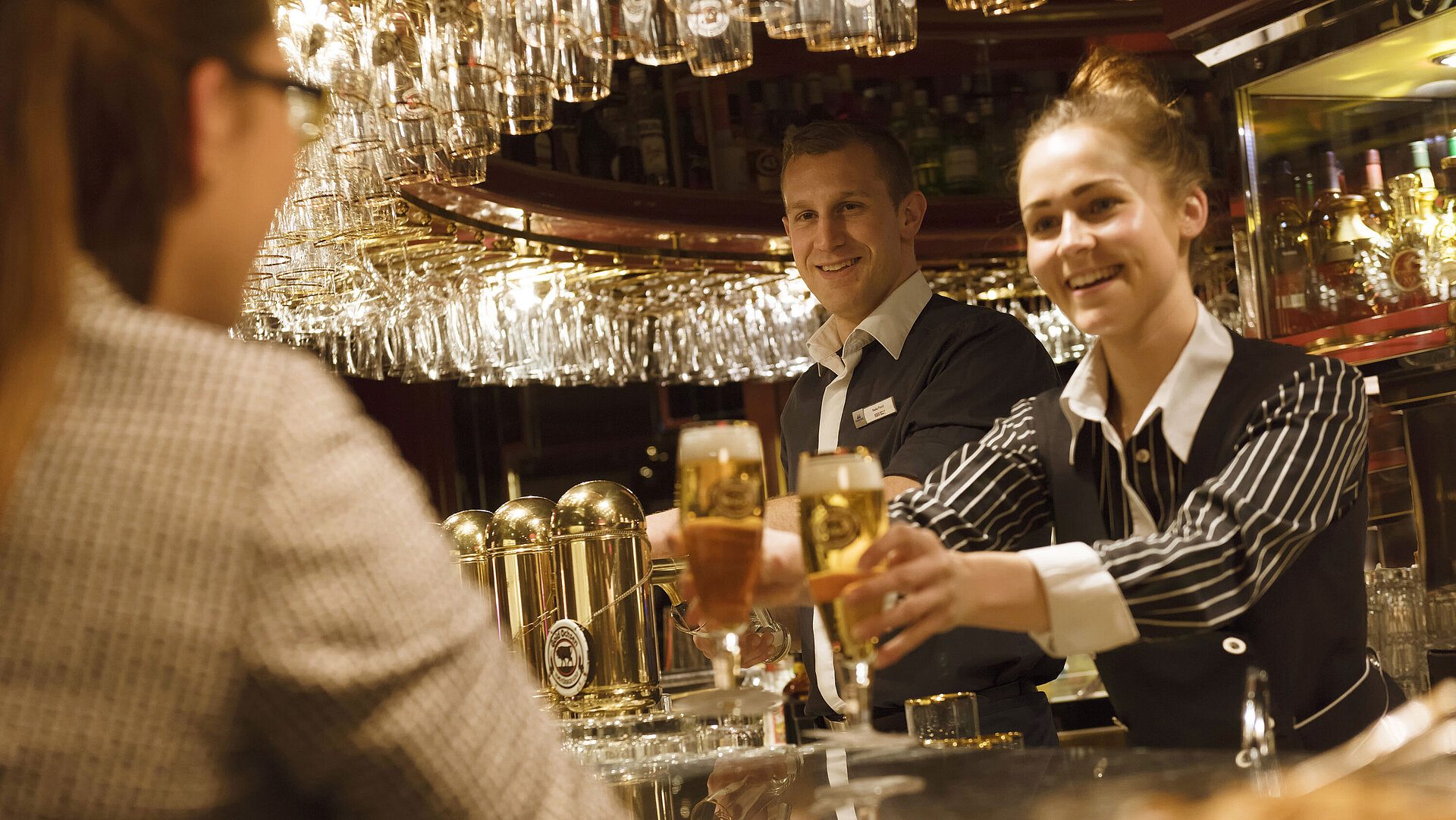 Pianobar Zwei Mitarbeitende servieren frisch gezapfte Getränke an der Bar im Maritim Hotel Ulm