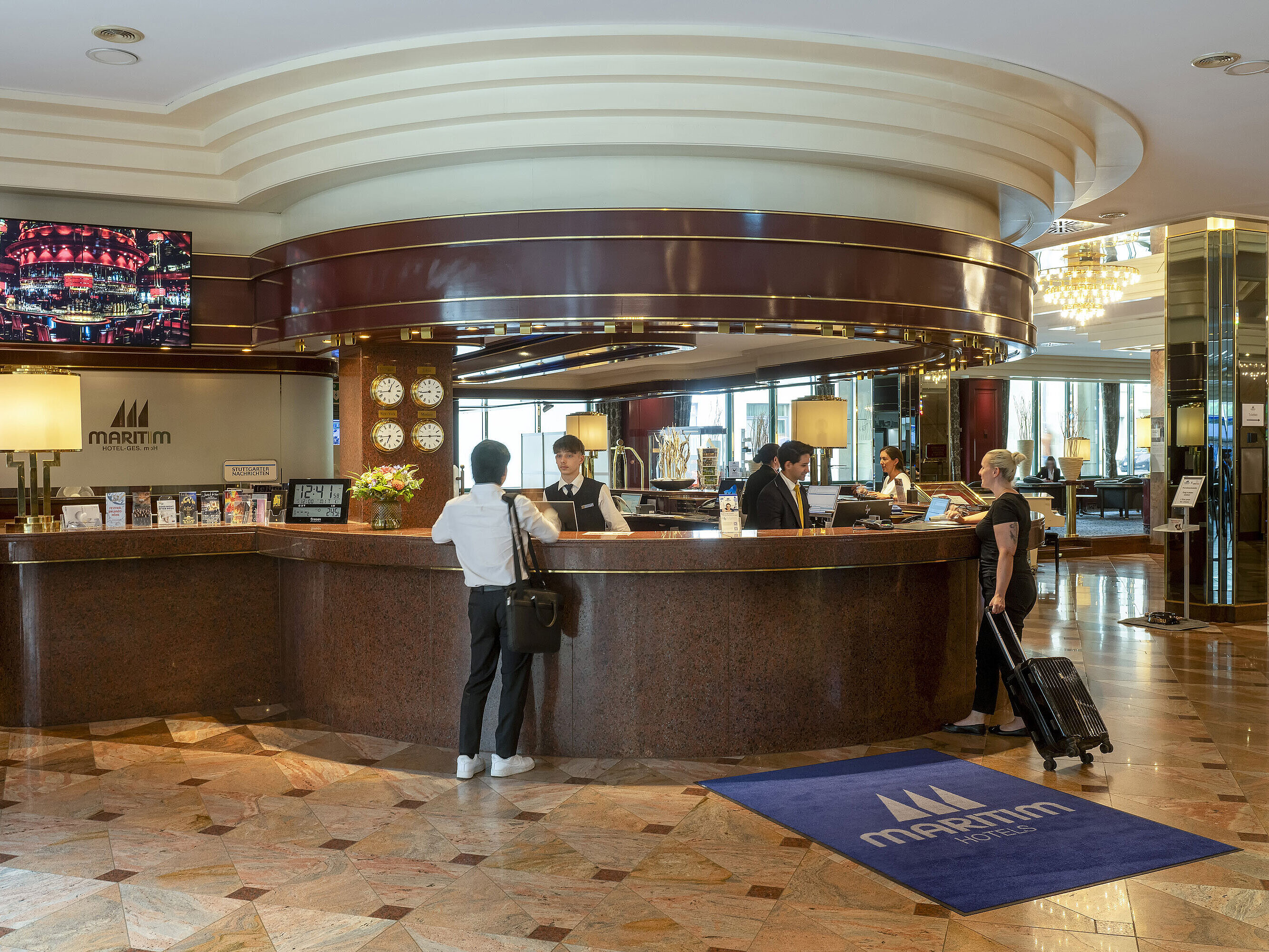 Gäste beim Check-in an der eleganten Rezeption im Maritim Hotel Stuttgart mit stilvollem Interieur.