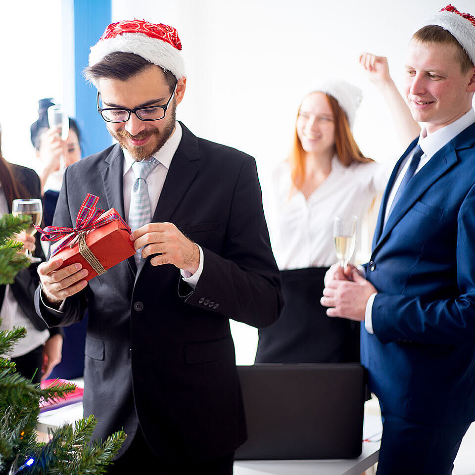 © Nichizhenova Elena - AdobeStock.com Kollegen beschenken sich bei einer Weihnachtsfeier im Hotel
