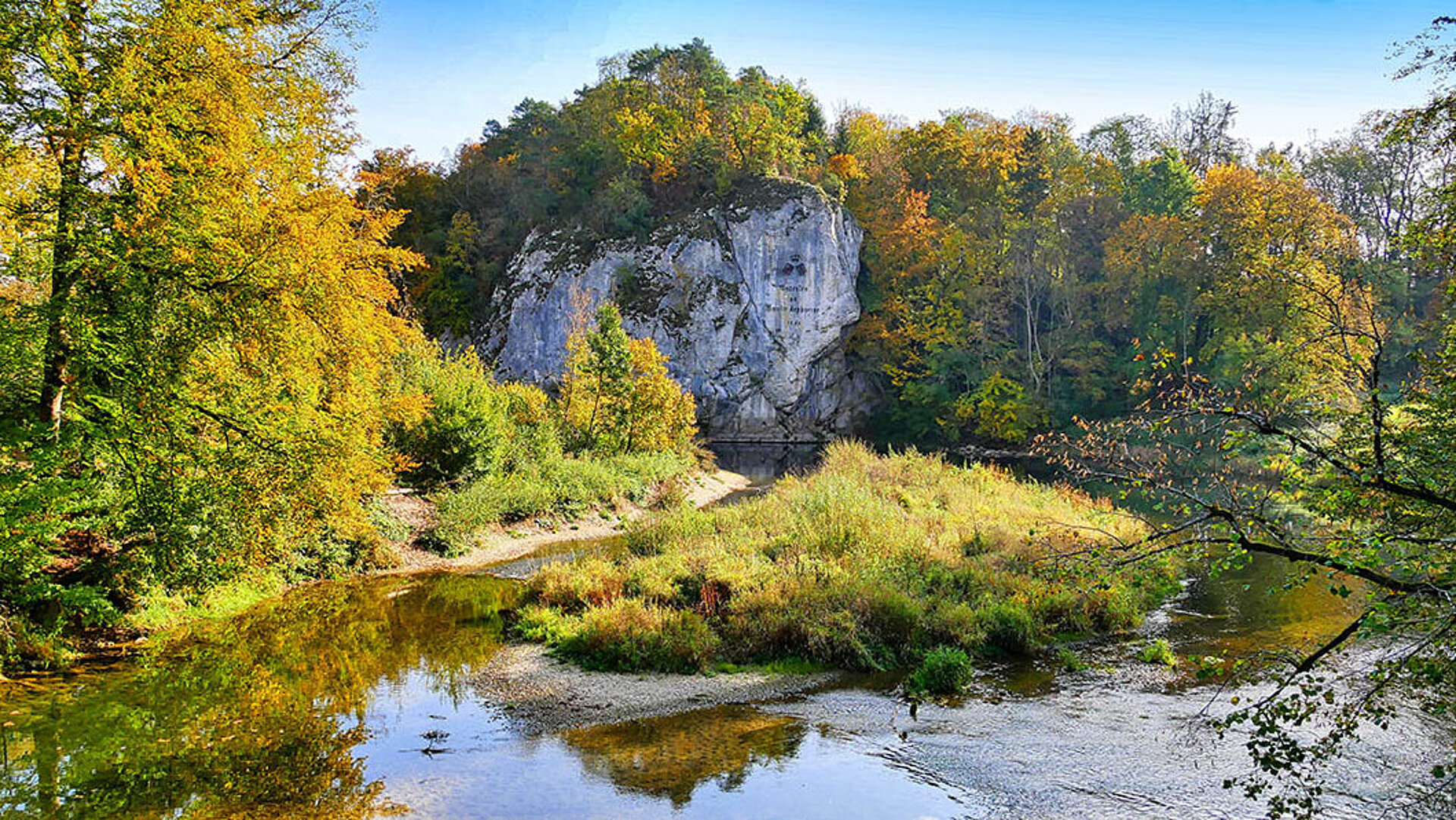 Amalienfelsen im Donautal umgeben von buntem Herbstwald und Flusslauf