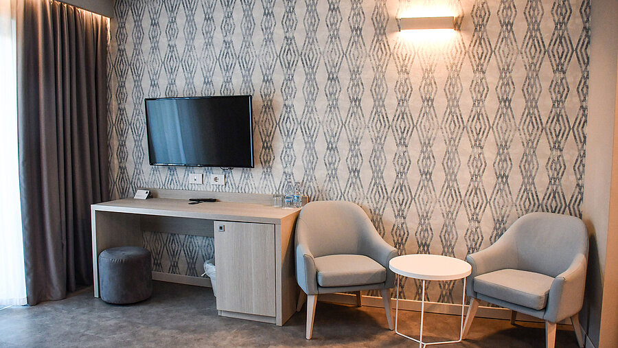 Moderner Sitzbereich mit Fernseher und Schreibtisch im Zimmer des Maritim Resort Calabria