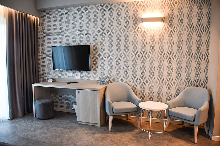 Moderner Sitzbereich mit Fernseher und Schreibtisch im Zimmer des Maritim Resort Calabria