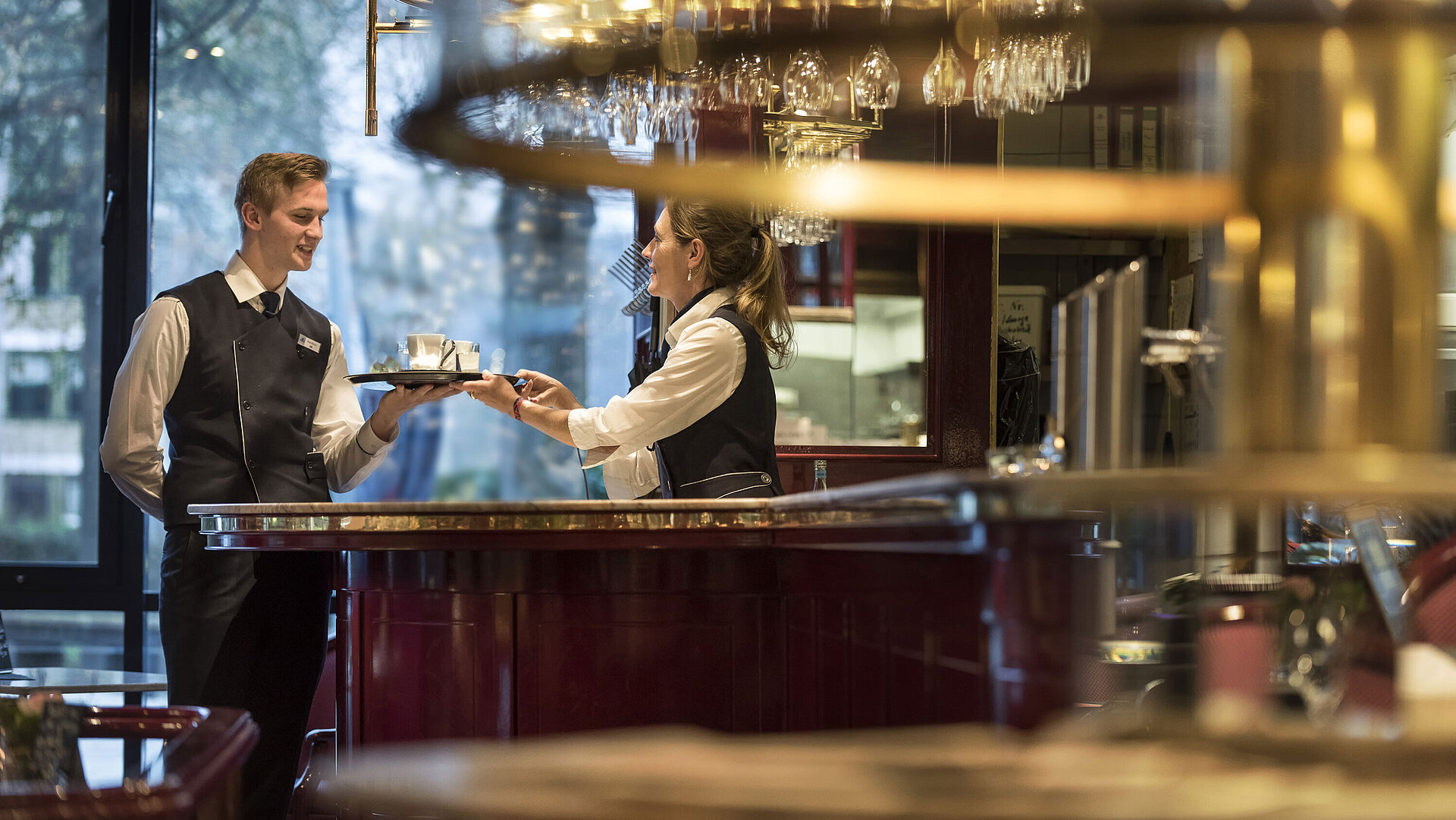 Freundliches Servicepersonal an der Bar der Brasserie im Maritim Hotel Bonn, das Getränkeservice mit einem Lächeln anbietet.