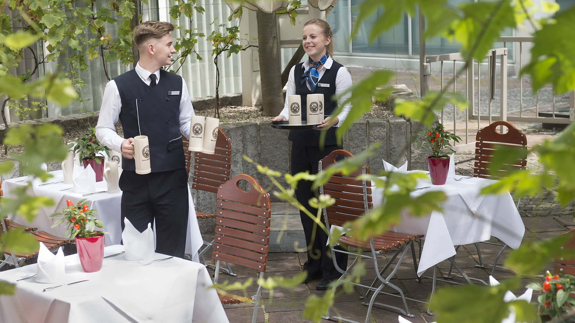 Biergarten Zwei freundliche Mitarbeitende servieren Bier im Biergarten des Maritim Hotel München
