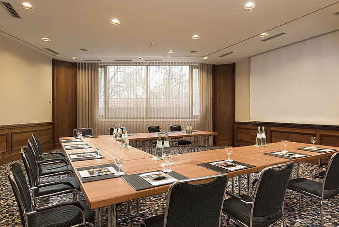 Freundlicher Konferenzraum mit U-Bestuhlung, Fensterfront und Leinwand im Maritim Hotel Ulm.