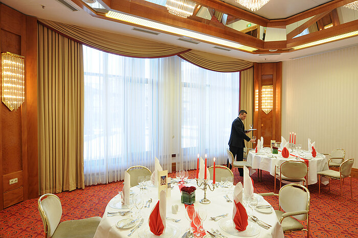 Exklusiv gedeckter Bankettsaal mit eleganten Kerzen und roten Servietten im Maritim Hotel Magdeburg.