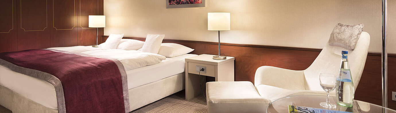 Classic Zimmer im Maritim Hotel Bonn, gemütlich eingerichtet mit Doppelbett, Sessel, Tisch und moderner Beleuchtung.