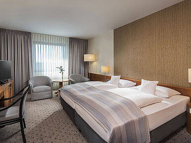 Modernes Classic Doppelzimmer mit gemütlichem Doppelbett, Sitzbereich und Schreibtisch im Maritim Hotel Hannover.