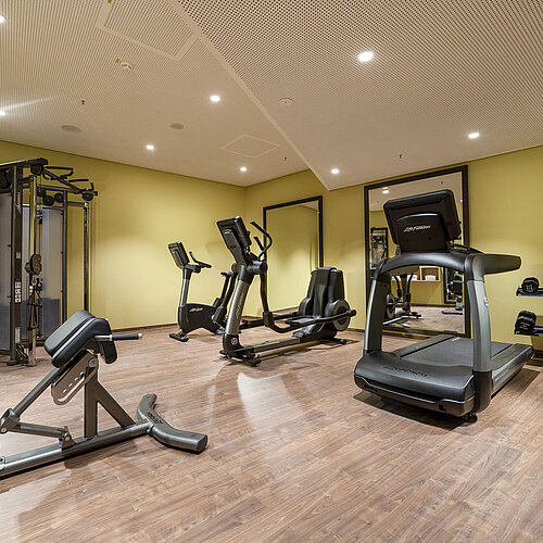 Modern ausgestatteter Fitnessraum im Maritim Hotel Ingolstadt mit Laufband, Hanteln und Trainingsgeräten.