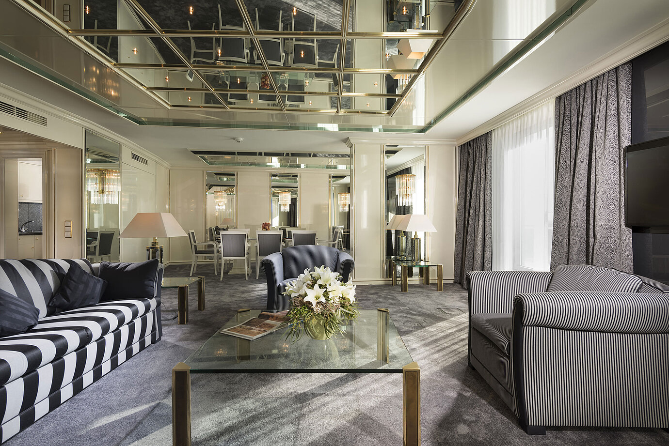 Luxuriöse Suite im Maritim Hotel Ulm mit verspiegelter Decke, stilvoller Sitzecke und Esstisch