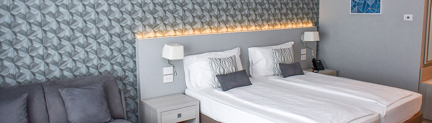 Großzügiges Zimmer im Maritim Resort Calabria mit Twin-Bett, Sofa und stilvoller Wandgestaltung
