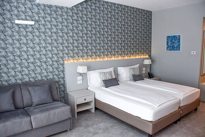 Großzügiges Zimmer im Maritim Resort Calabria mit Twin-Bett, Sofa und stilvoller Wandgestaltung