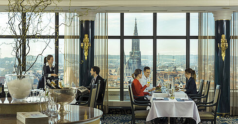 Gäste genießen das Essen mit Blick auf das Ulmer Münster im Panorama-Restaurant des Maritim Hotel Ulm