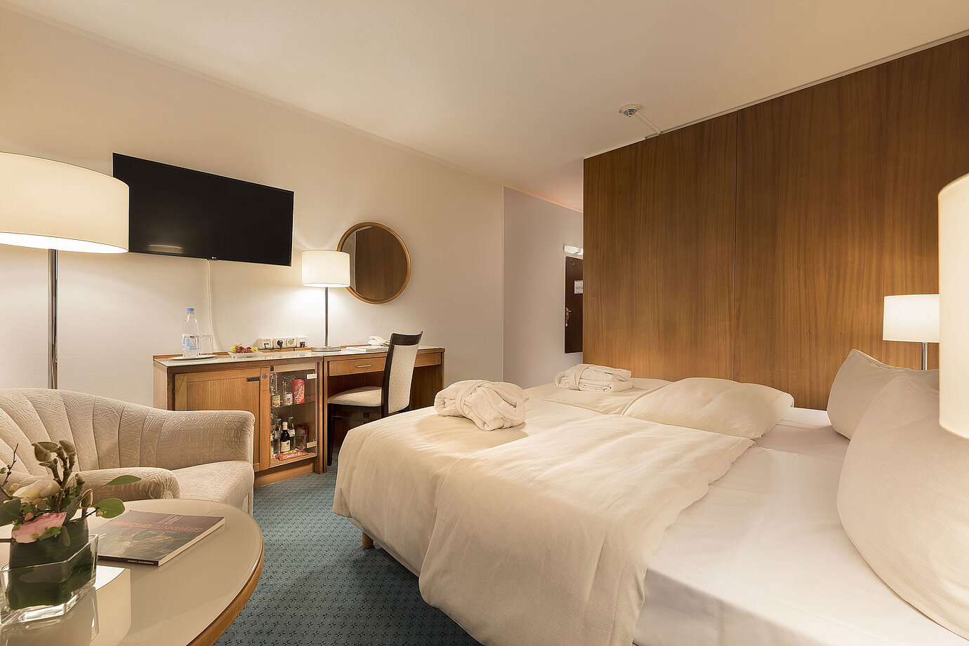 Classic Zimmer im Maritim Seehotel Timmendorfer Strand mit zwei Betten, Minibar, Schreibtisch, TV und Sitzgelegenheit.