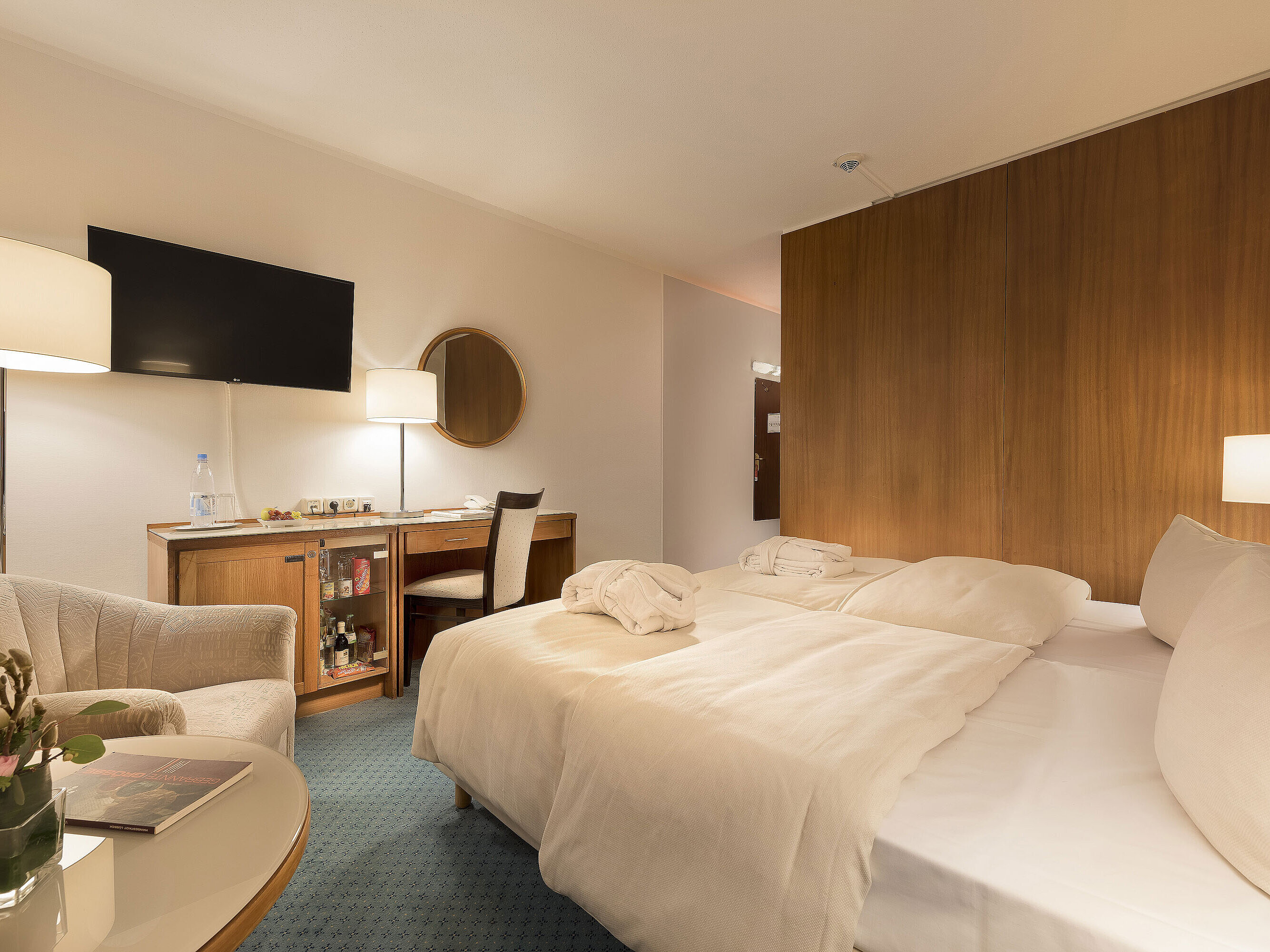 Classic Zimmer im Maritim Seehotel Timmendorfer Strand mit zwei Betten, Minibar, Schreibtisch, TV und Sitzgelegenheit.