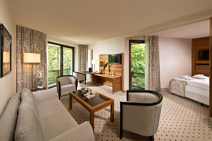 Geräumige Suite im Maritim Hotel Bad Homburg mit separatem Wohnbereich, Balkon und grünem Ausblick.