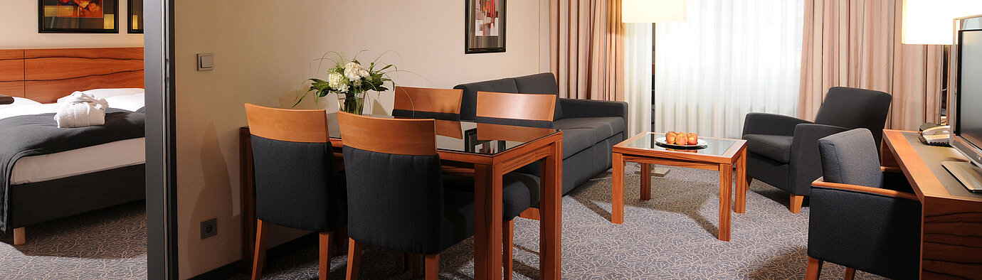 Großzügige Suite mit Wohnzimmer, Esstisch und separatem Schlafzimmer im Maritim Hotel München