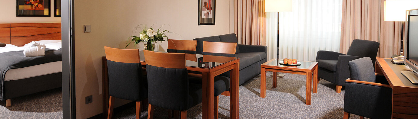 Großzügige Suite mit Wohnzimmer, Esstisch und separatem Schlafzimmer im Maritim Hotel München