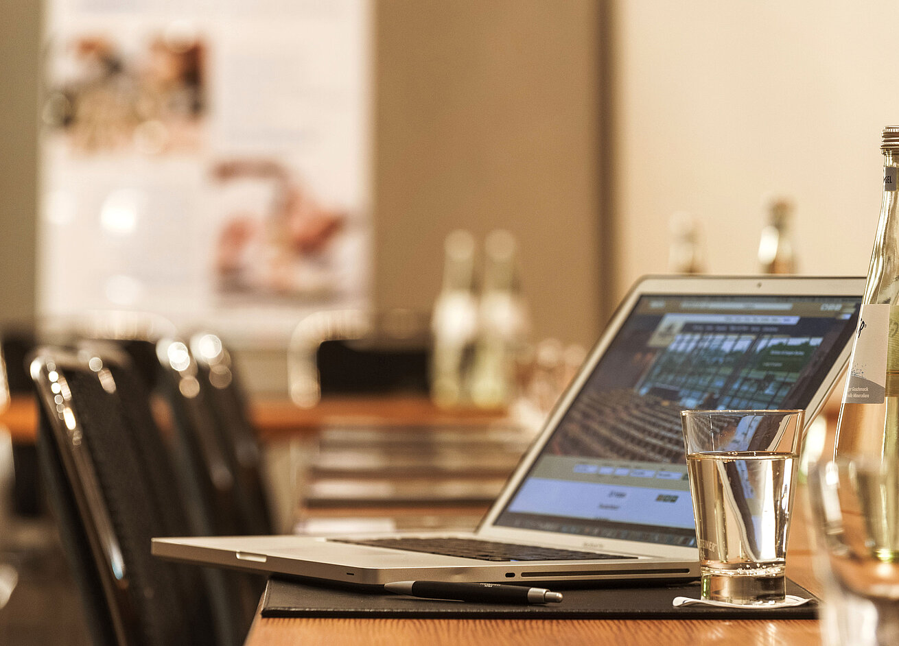 Laptop, Stift und Wasserglas auf Tisch im Konferenzraum des Maritim Hotel München