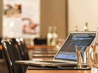Laptop, Stift und Wasserglas auf Tisch im Konferenzraum des Maritim Hotel München