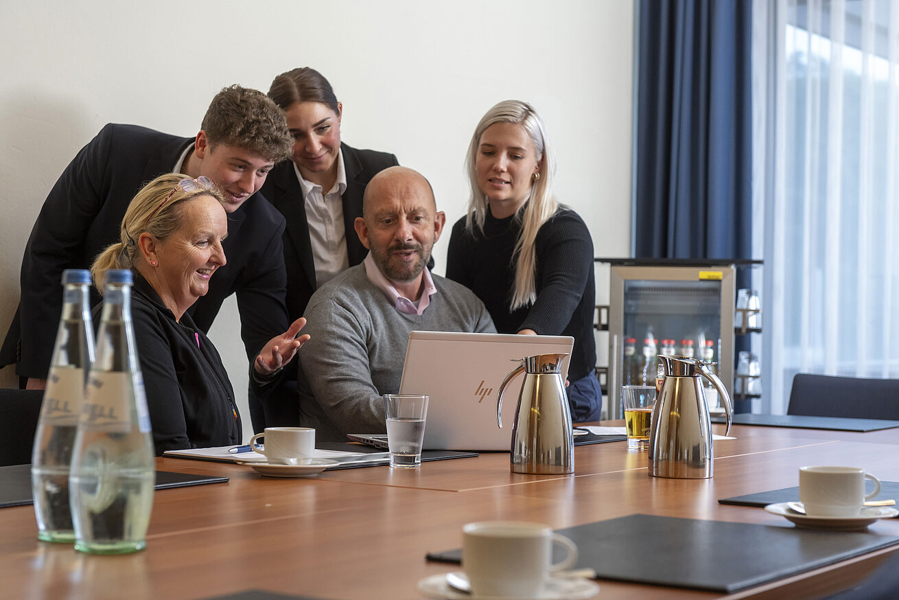 Gruppe im Konferenzraum beim Arbeiten am Laptop, freundliche Atmosphäre im Maritim Hotel Travemünde
