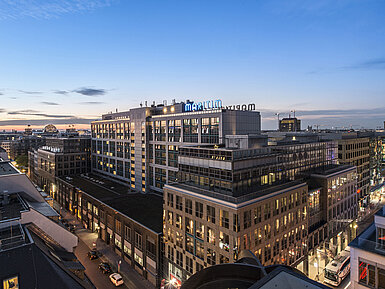 Blick auf das Maritim proArte Hotel Berlin bei Dämmerung, umgeben von modernen Gebäuden im Herzen Berlins.