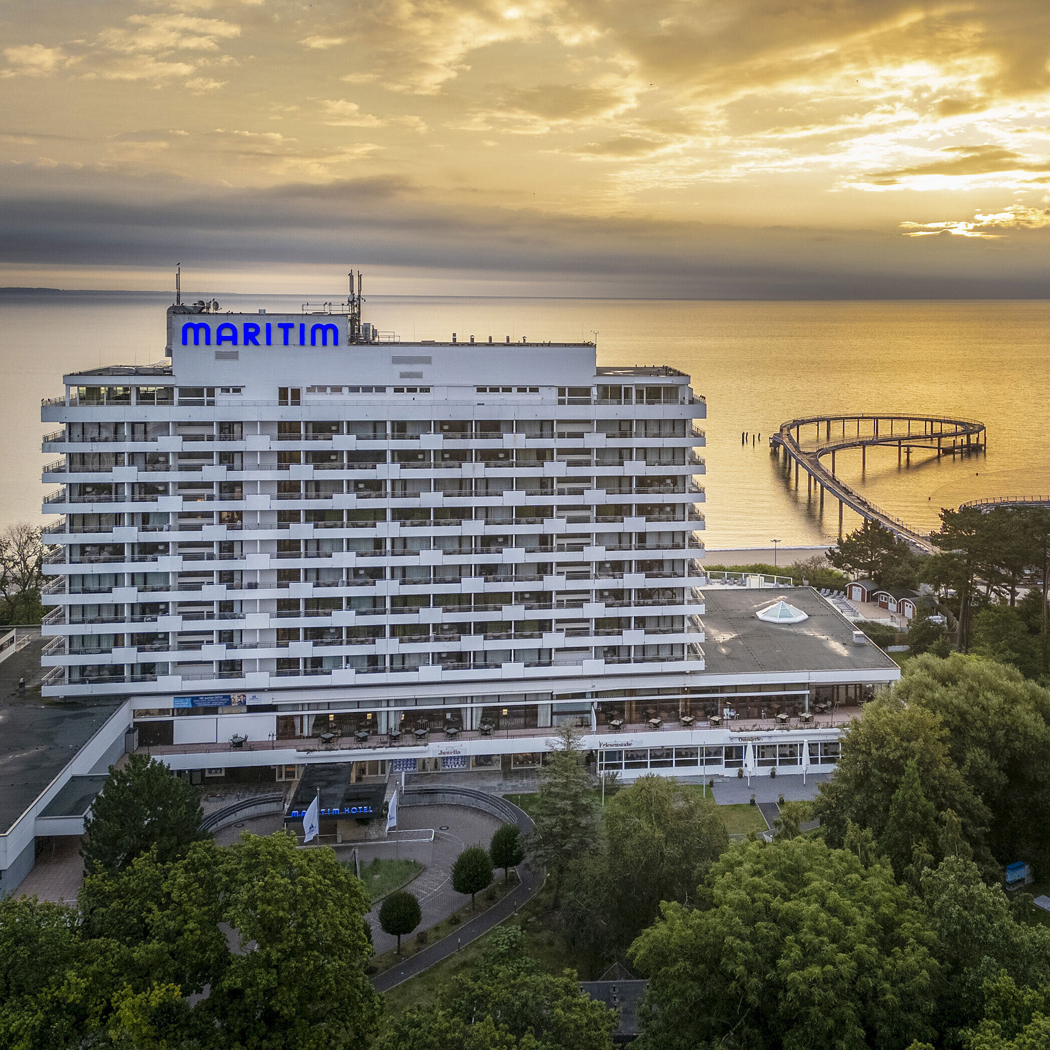 Maritim Seehotel Timmendorfer Strand bei Sonnenaufgang mit Seebrücke und Meerblick.