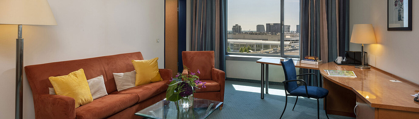 Junior Suite Junior Suite im Maritim Hotel Frankfurt mit separatem Wohnbereich, Sofa, Schreibtisch und Panoramablick auf die Stadt.