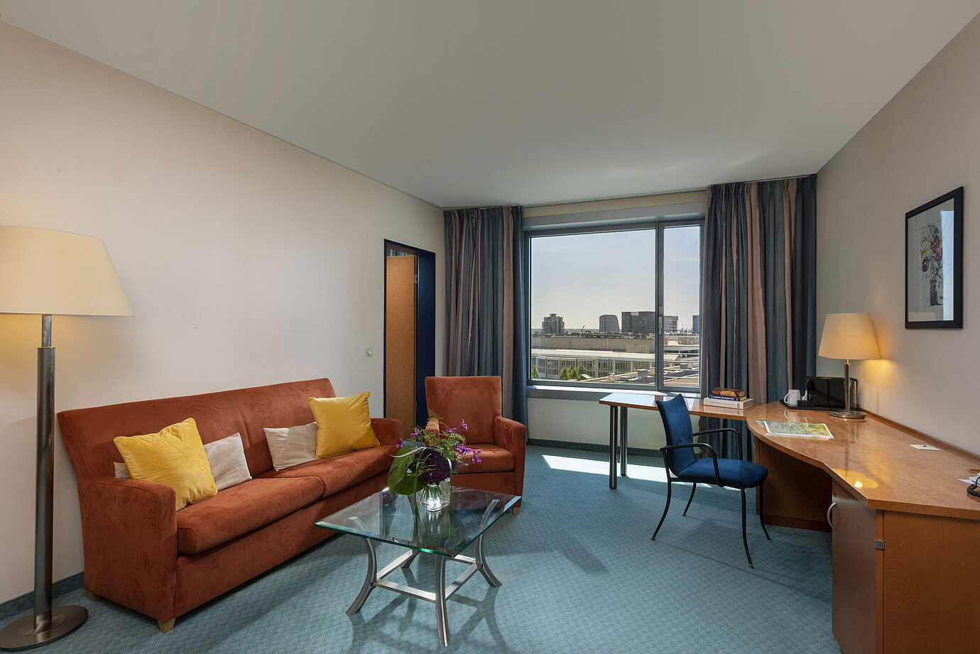 Junior Suite im Maritim Hotel Frankfurt mit separatem Wohnbereich, Sofa, Schreibtisch und Panoramablick auf die Stadt.