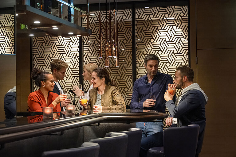 Gäste genießen Drinks und gesellige Gespräche in der stilvollen Bar des Maritim Hotel Ingolstadt.