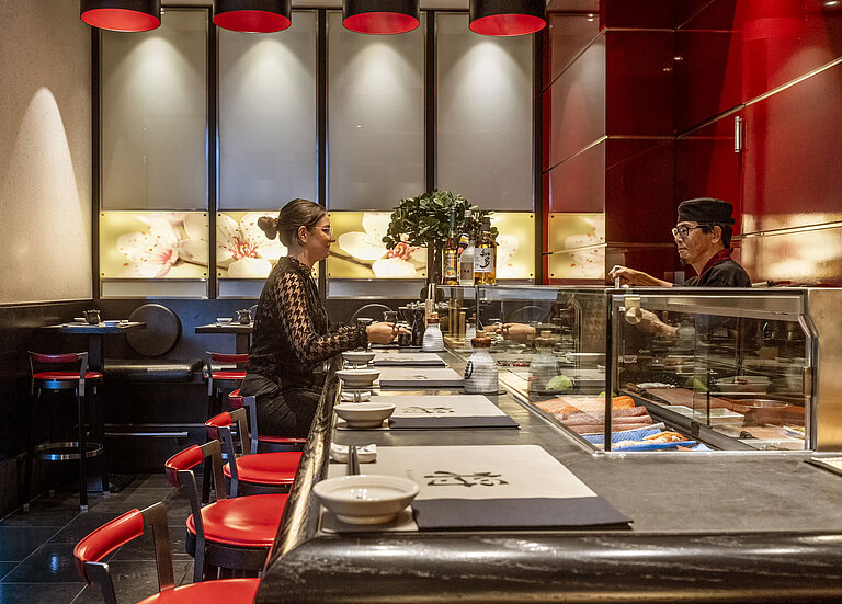 Gast genießt frisches Sushi an der eleganten Sushi-Bar "SushiSho" im Maritim Hotel Düsseldorf mit authentischer Atmosphäre.
