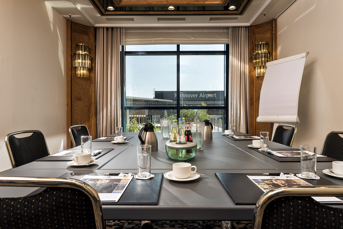 Heller Besprechungsraum mit Konferenztisch, Getränken und Blick auf den Flughafen im Maritim Hotel Hannover.