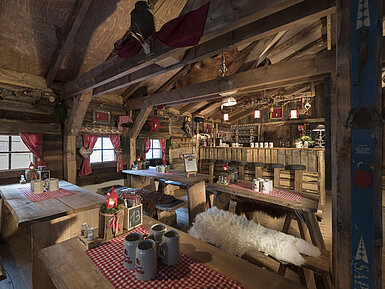 Rustikale Bar und festlich gedeckte Holztische mit roten Vorhängen in der Maritim Alm Stuttgart